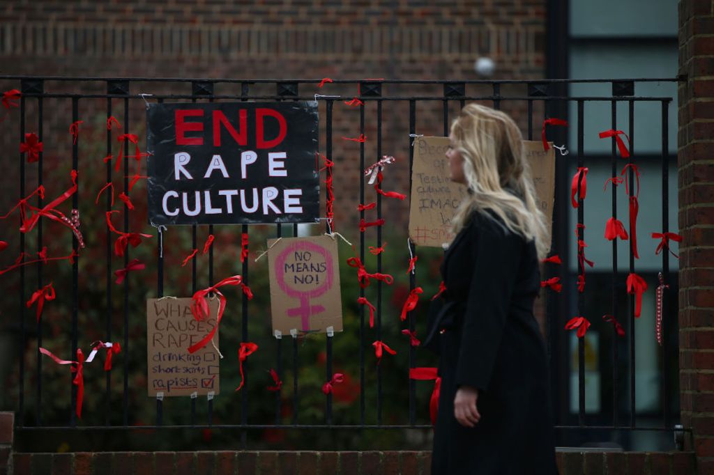 A woman walks past a placard saying 'End Rape Culture' attached to the fence outside James Allen's Girls' School (JAGS)