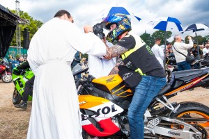 priest bless motorcycle rider at Le Pardon des Motards pilgrimage in porcaro brittany france